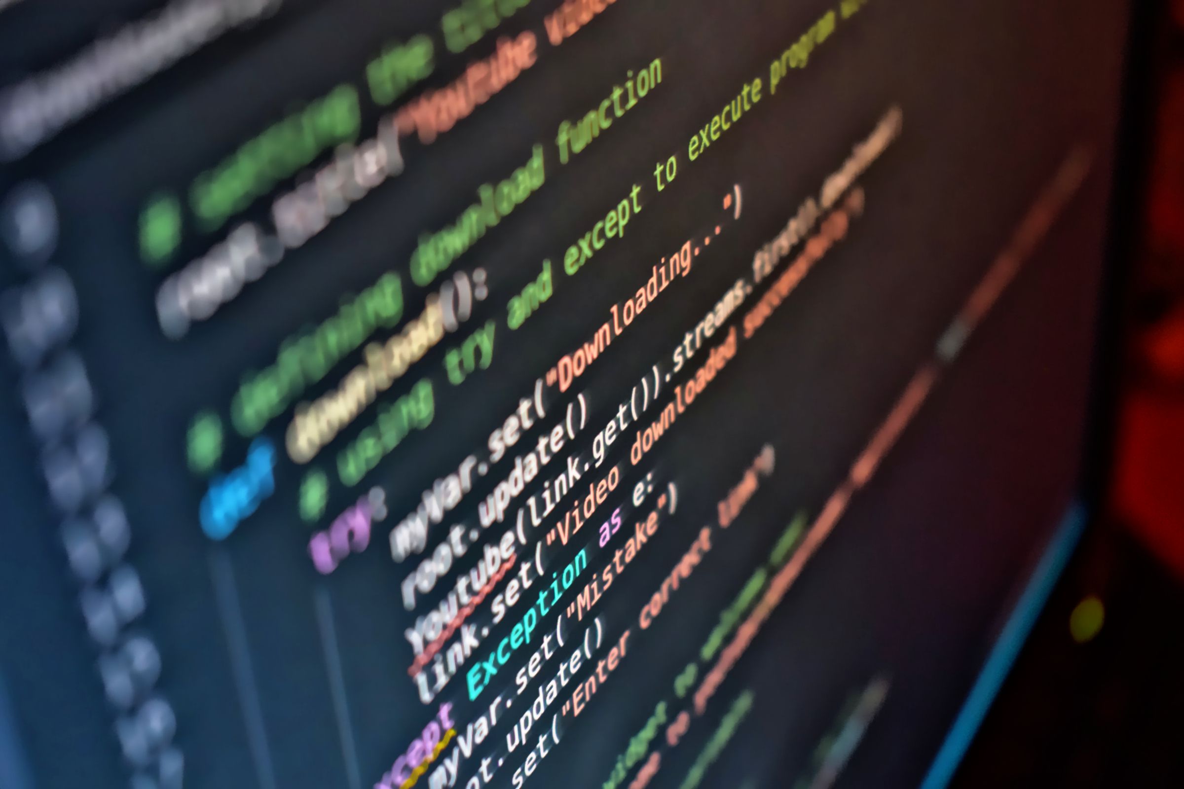 Lines of colour-highlighted program code on a dark monitor, seen at an angle.