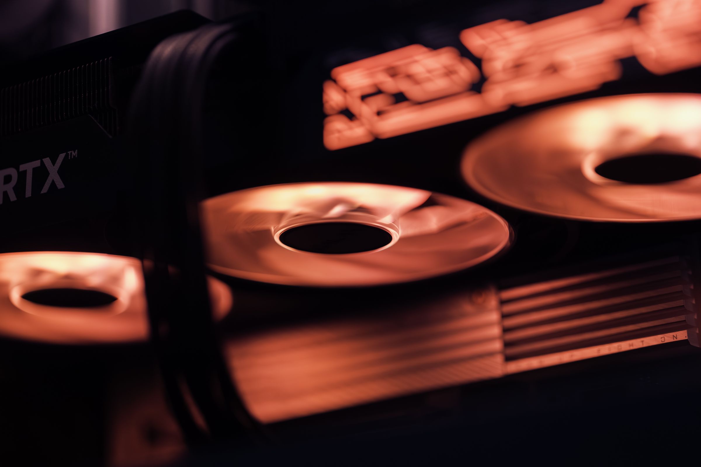 A close view of a graphics card with orange-lit fans and a copper-toned heat sink in a dark case.