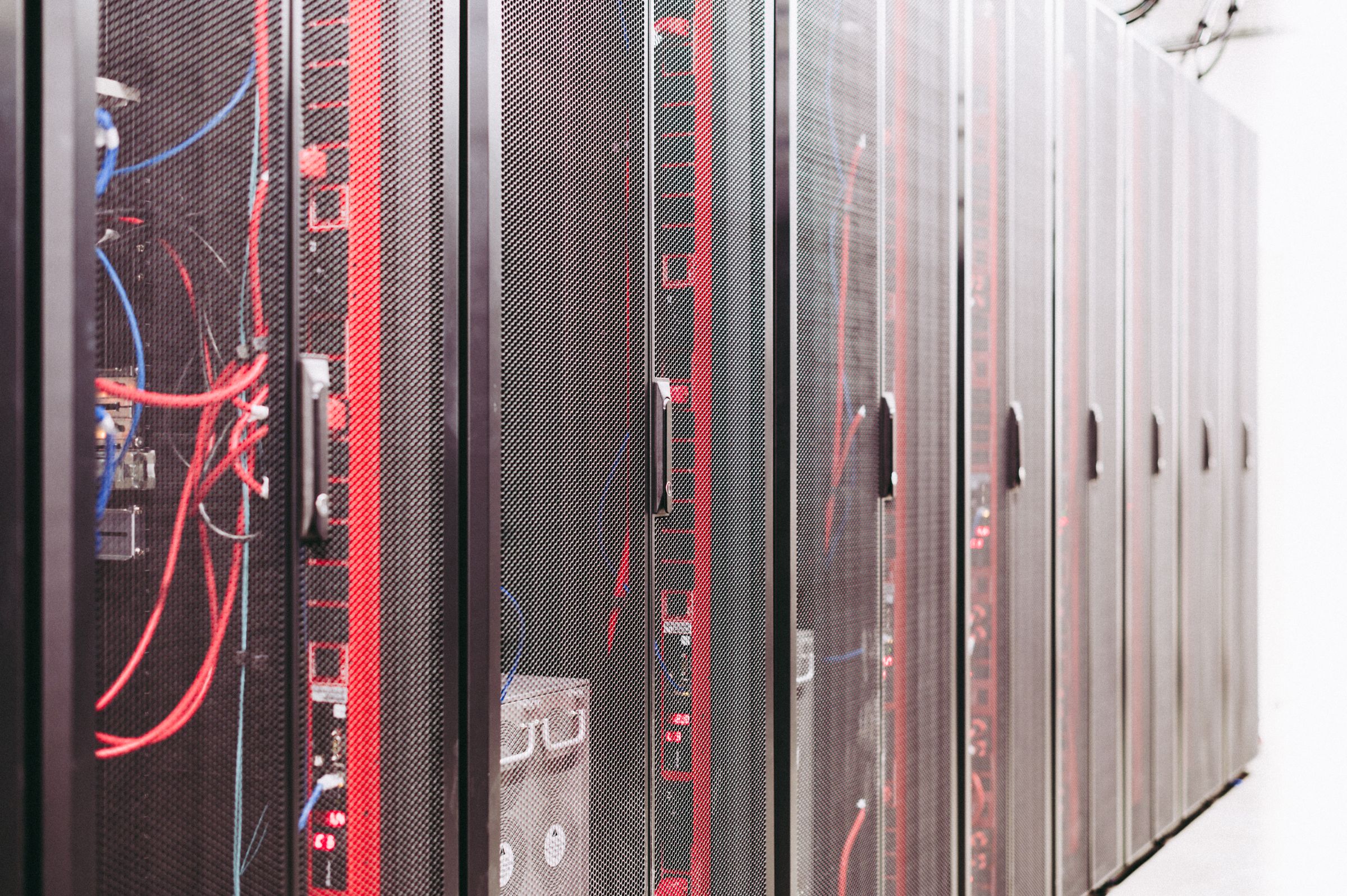 A row of tall server cabinets with red network cables visible behind the doors.