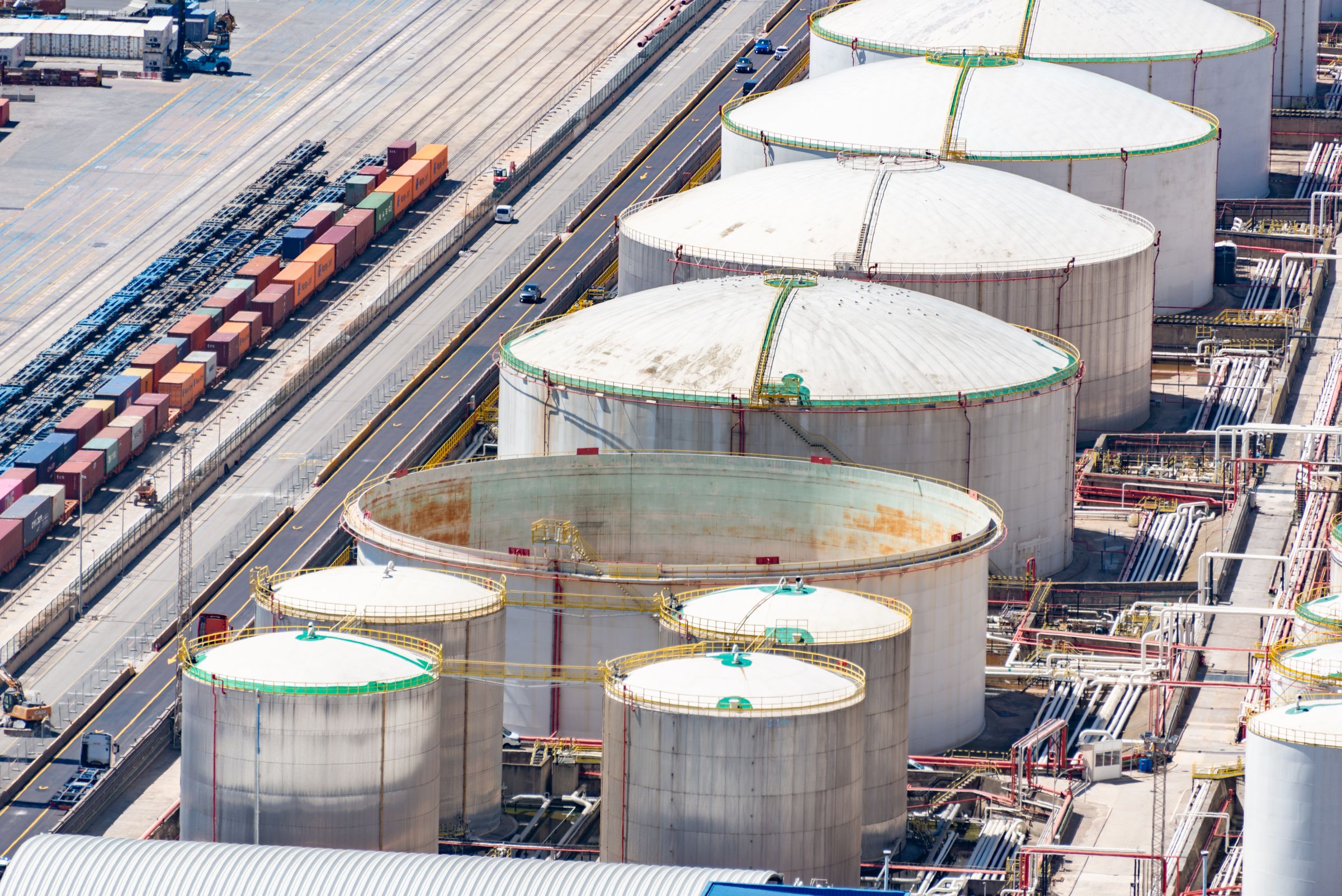 An aerial view of large white storage tanks beside railway sidings with lines of wagons.