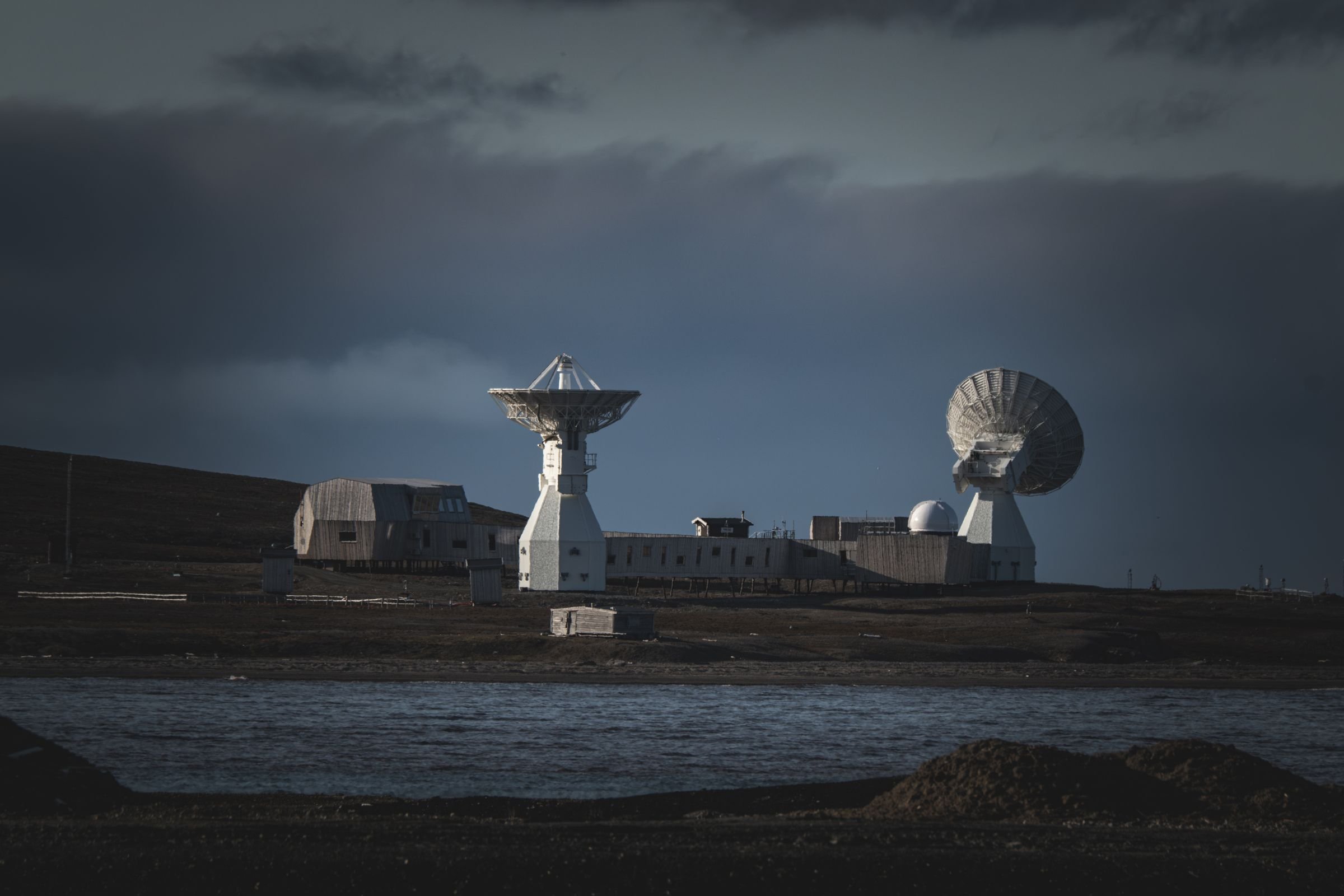 Satellite ground station dishes under a dark night sky