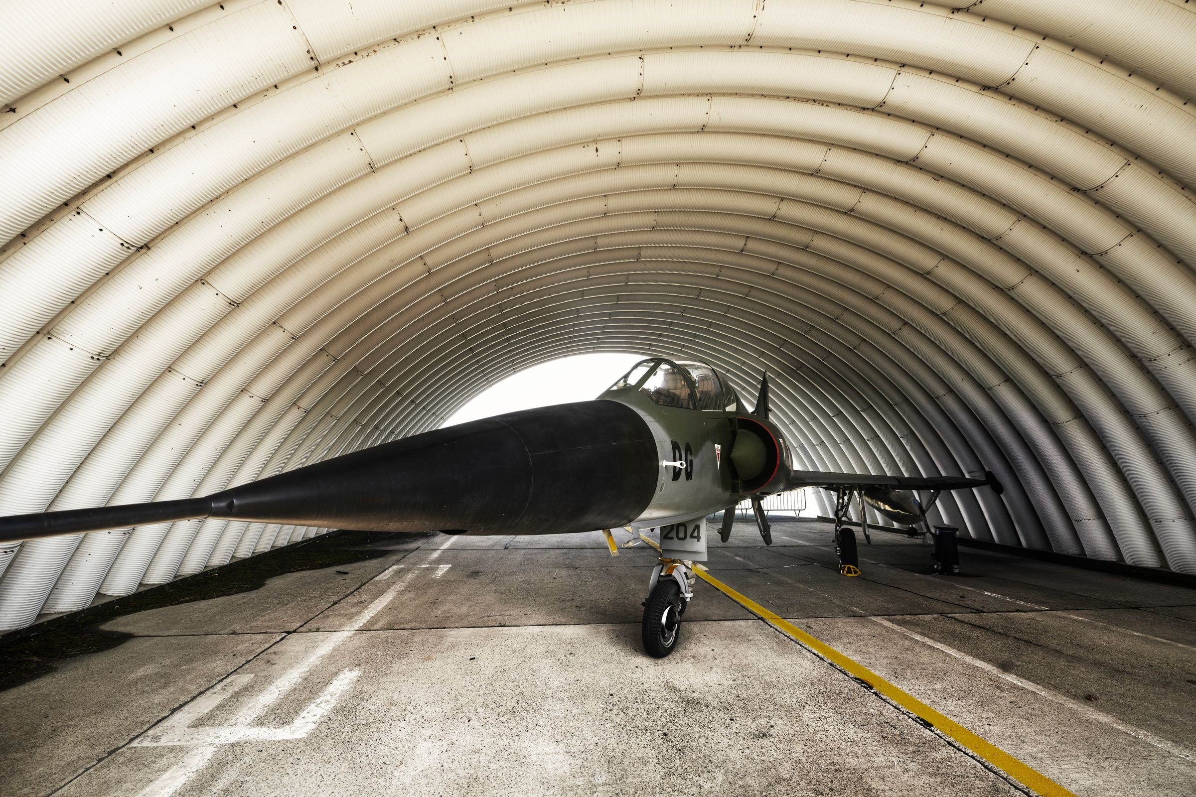 A fighter jet parked inside an arched hangar