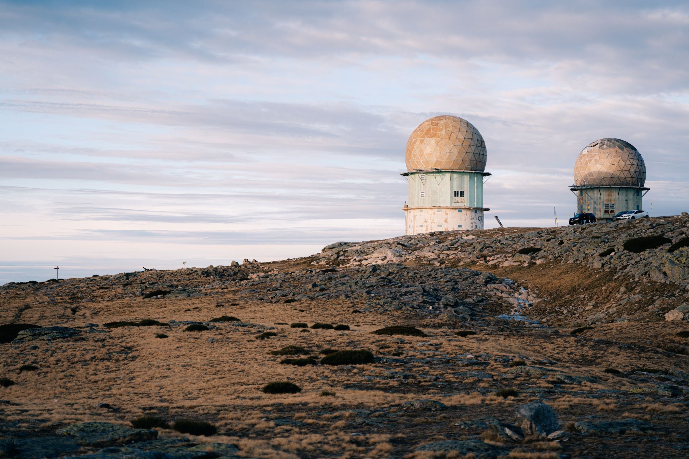 Two radar domes on a rocky hillside at twilight