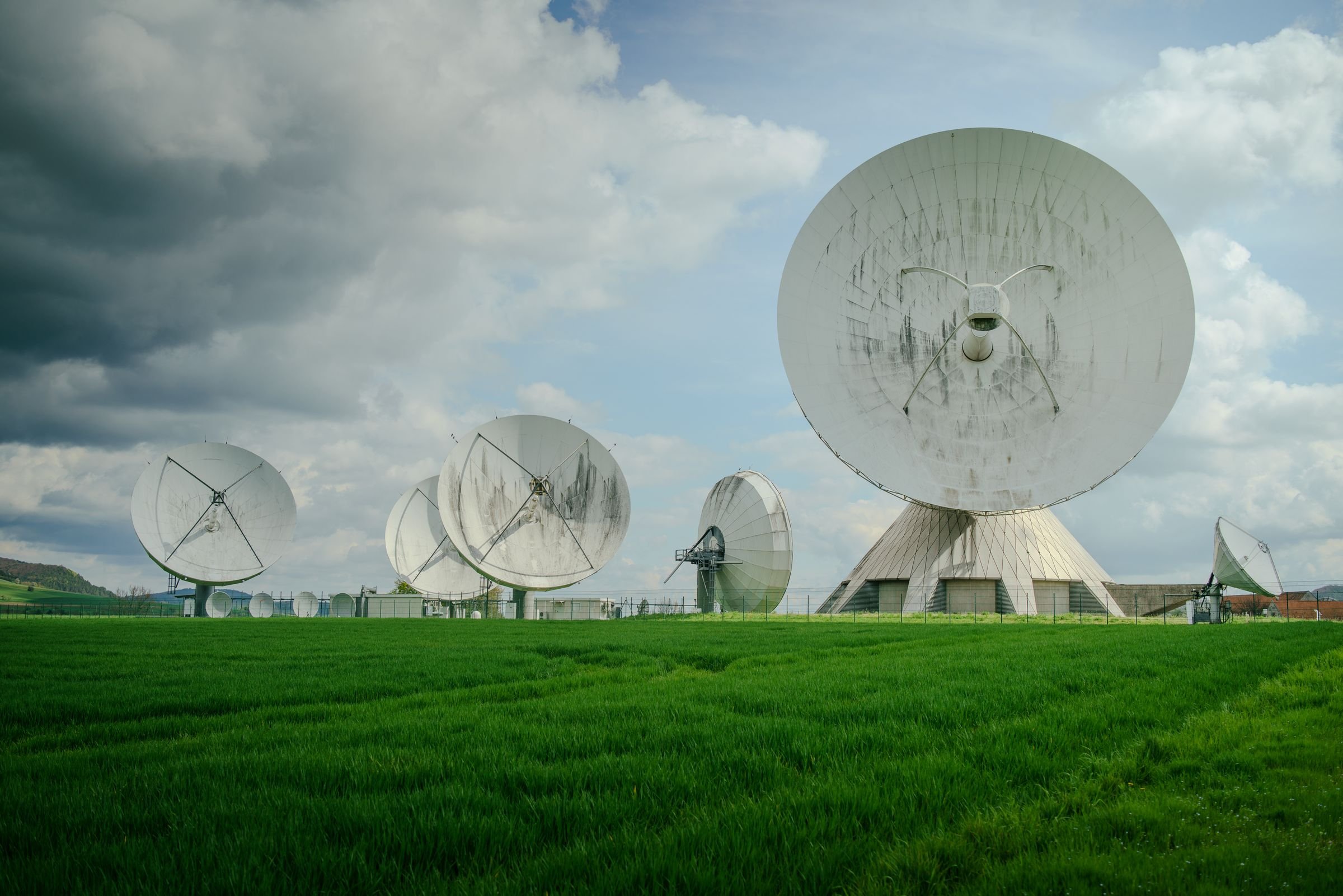 An array of large satellite dishes in a green field