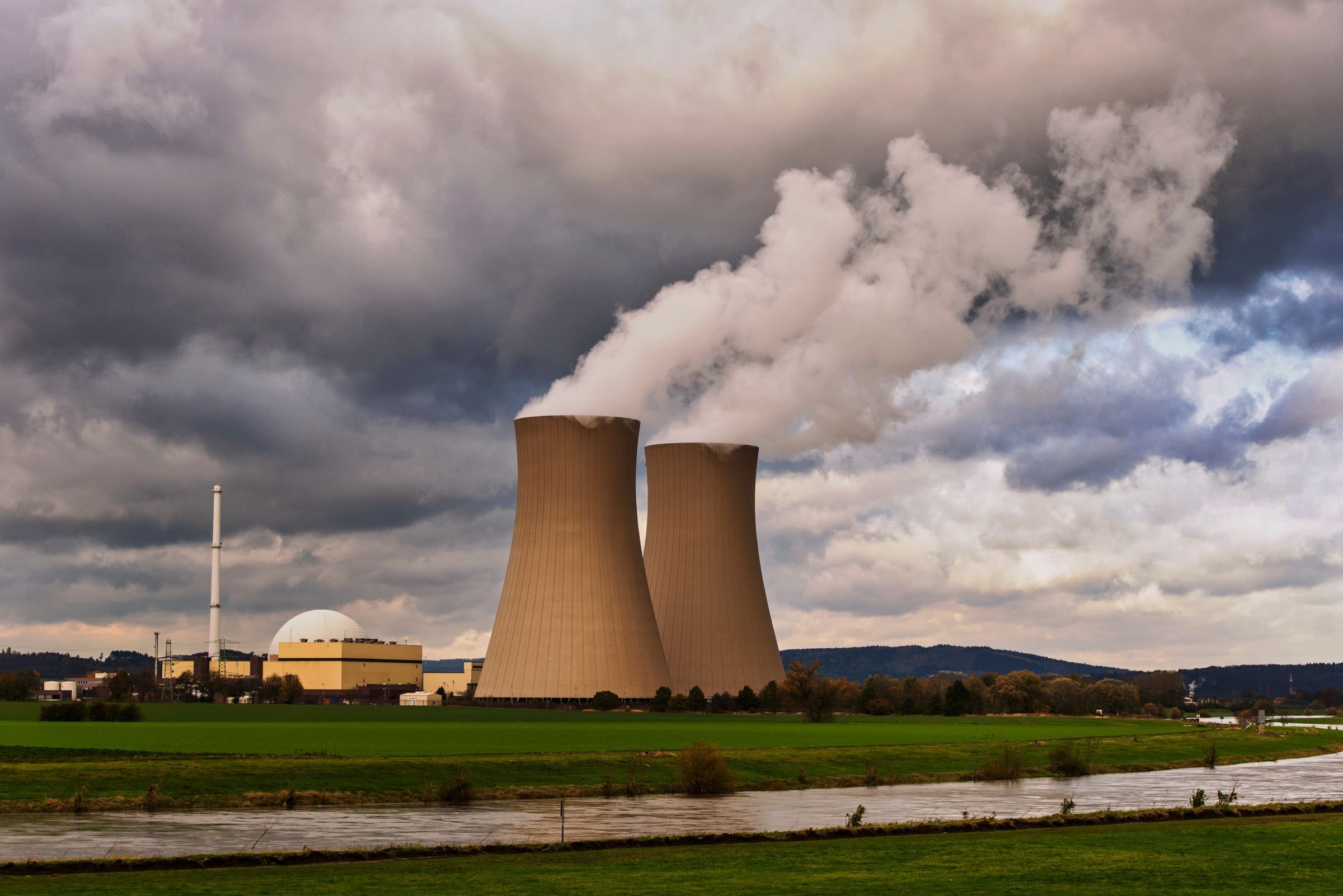 Steam rising from the cooling towers of a nuclear power station beside a river