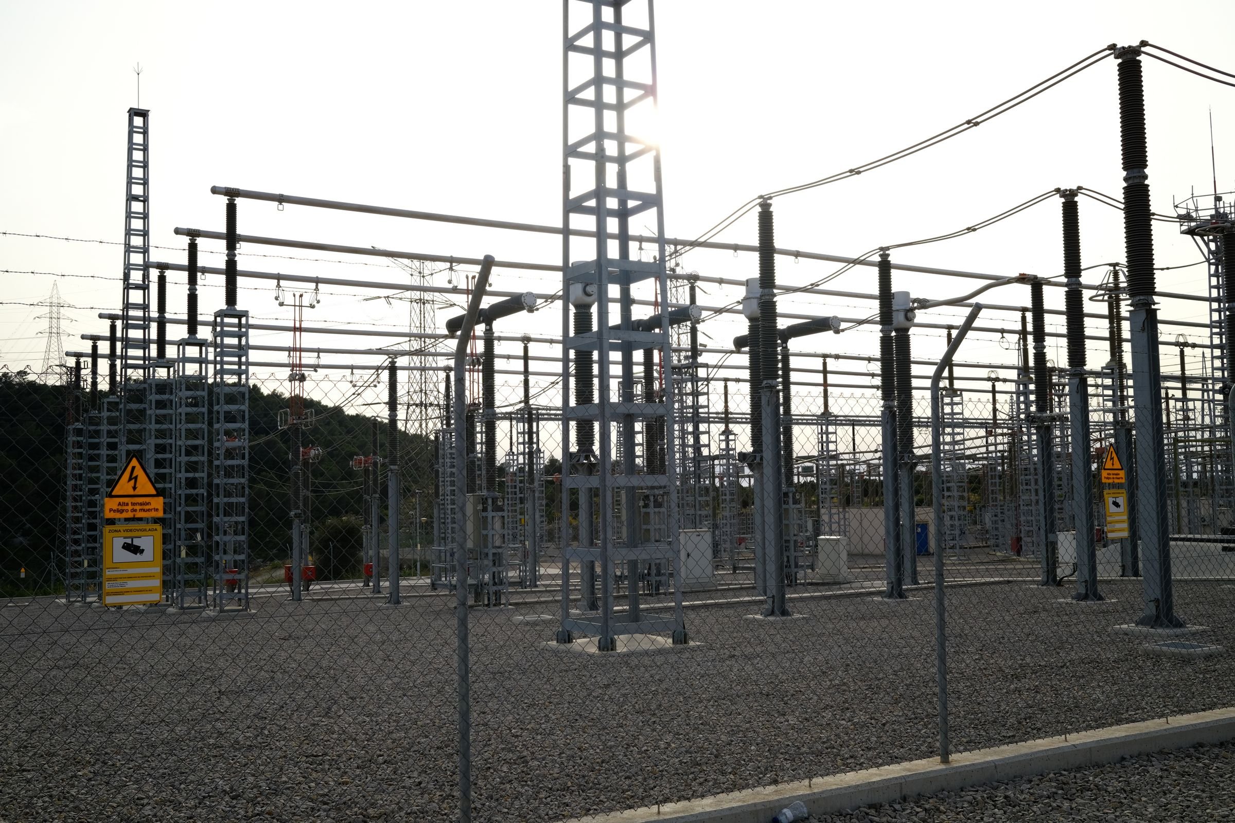 High-voltage equipment and warning signs at an outdoor electrical substation