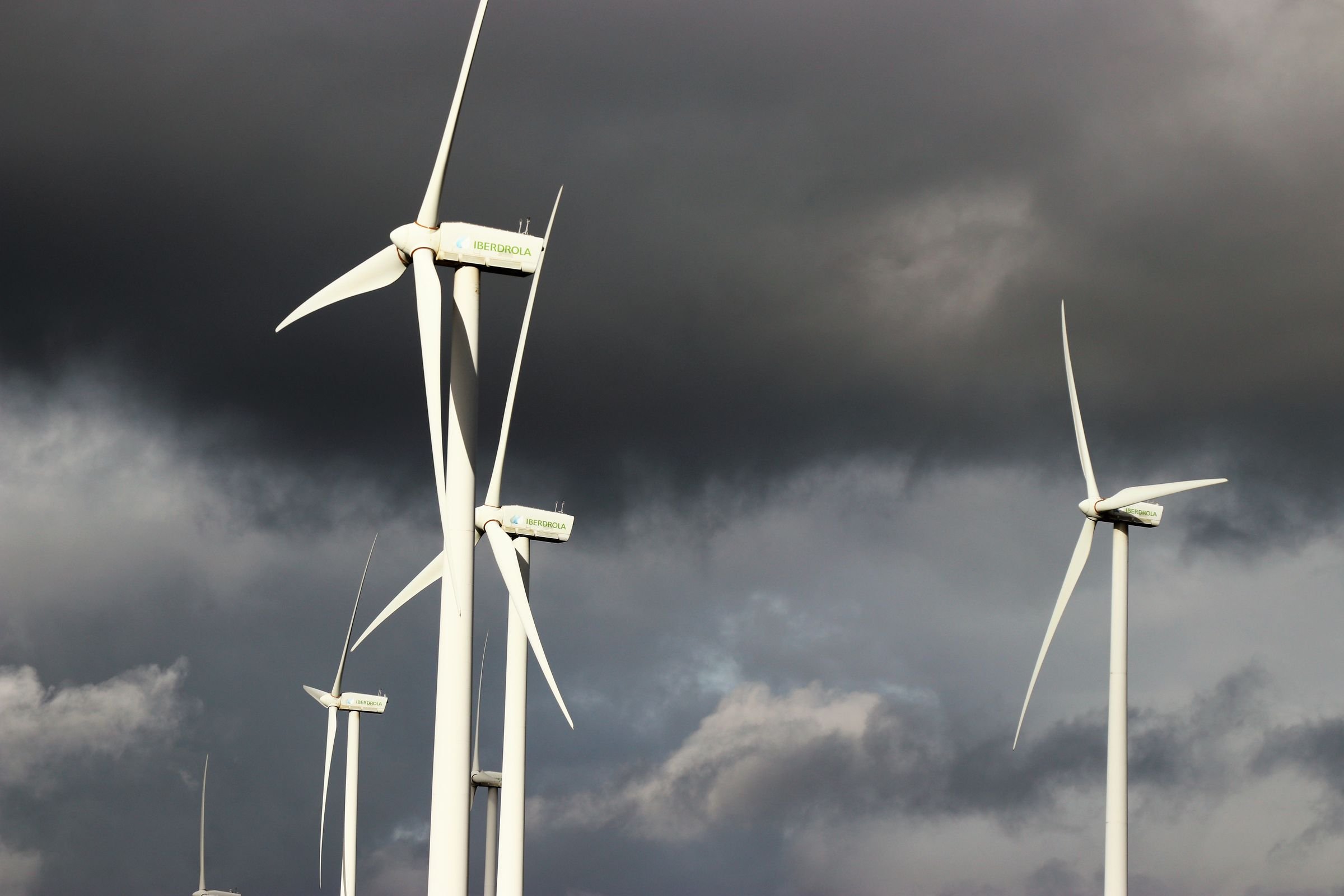 Wind turbines turning beneath dark storm clouds