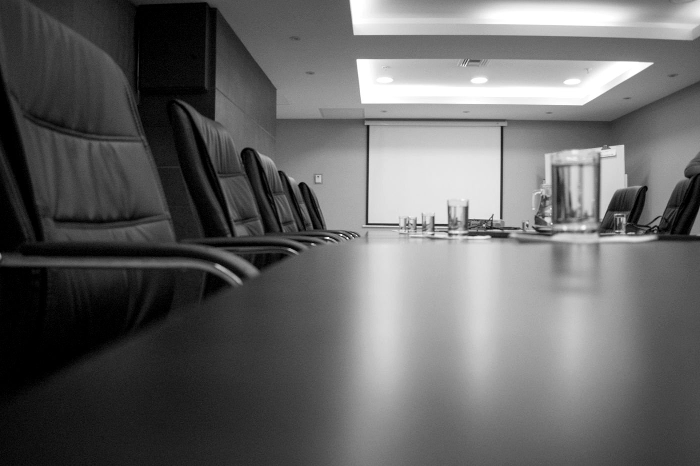 An empty boardroom with leather chairs around a long table