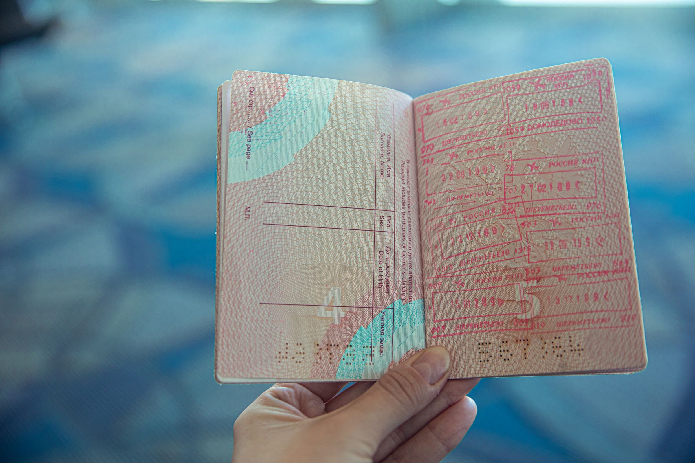 A hand holding open a passport filled with stamps.
