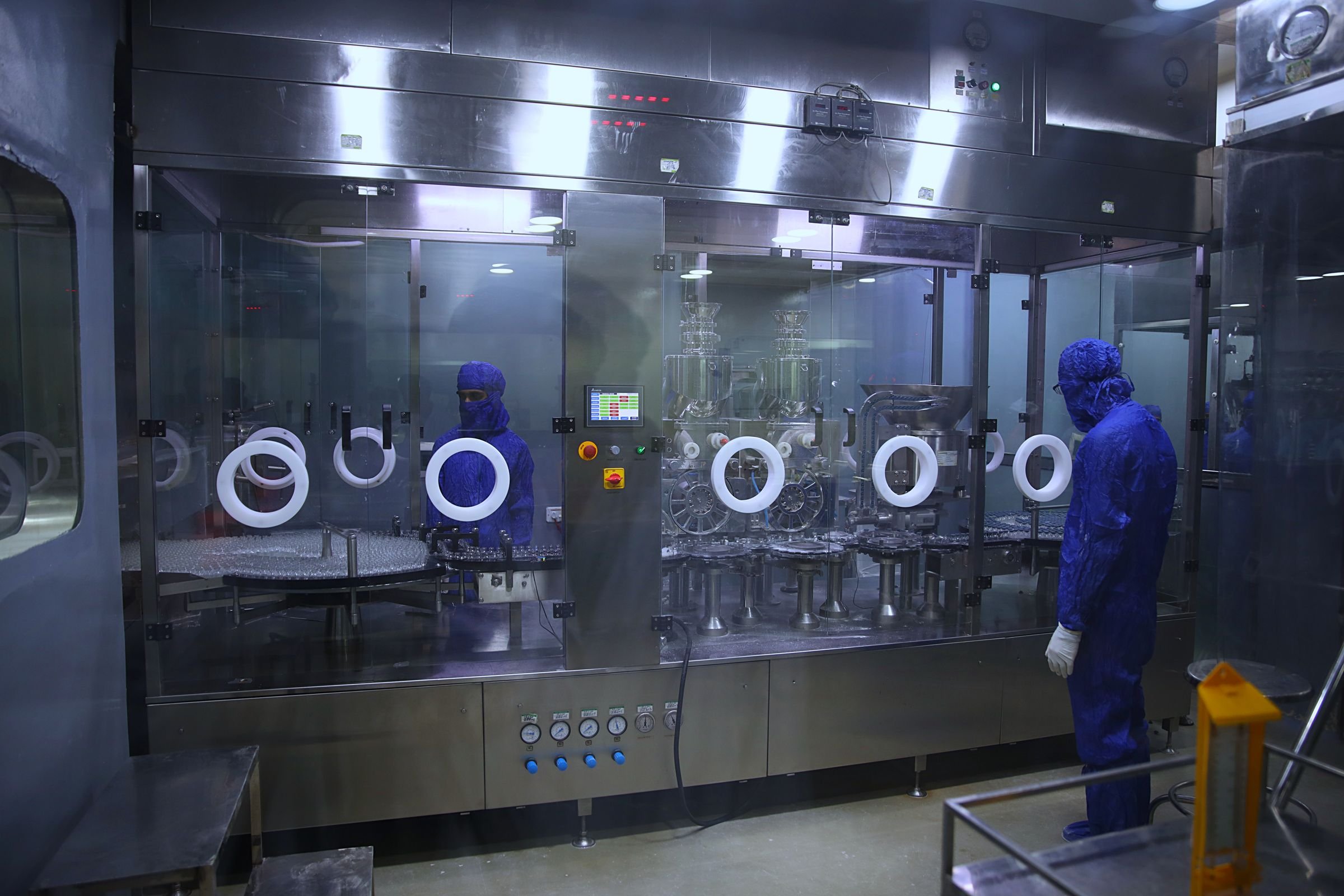 Workers in protective suits at a sterile pharmaceutical production line