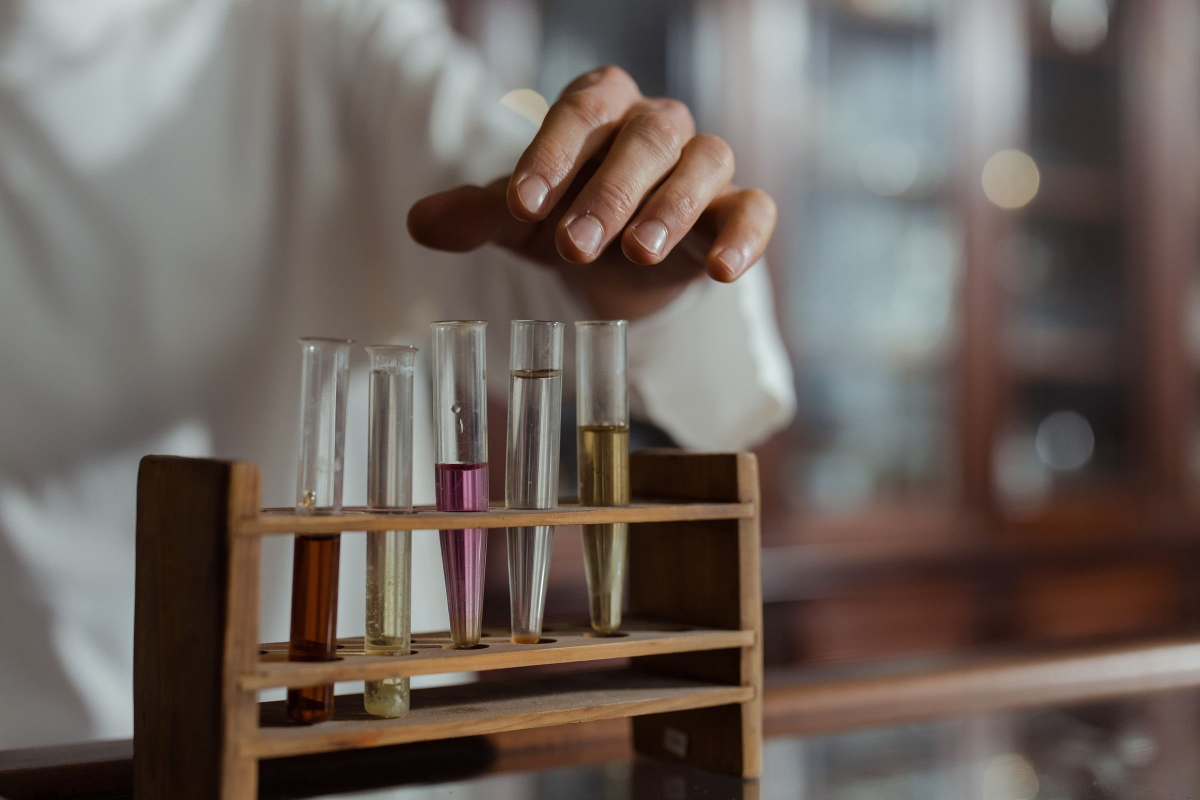A hand lifting a test tube from a rack in a laboratory