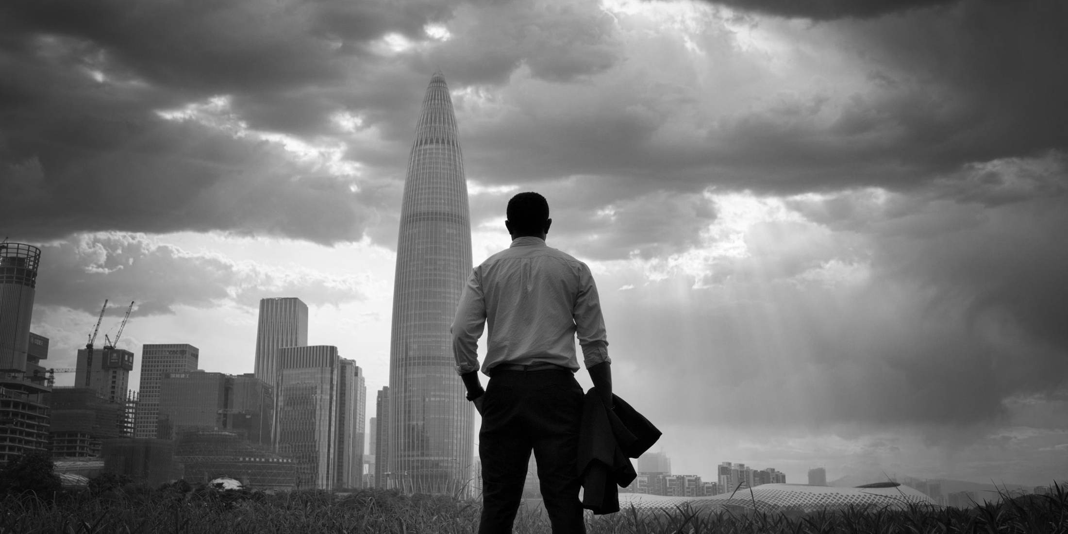 A city skyline under storm clouds, in black and white
