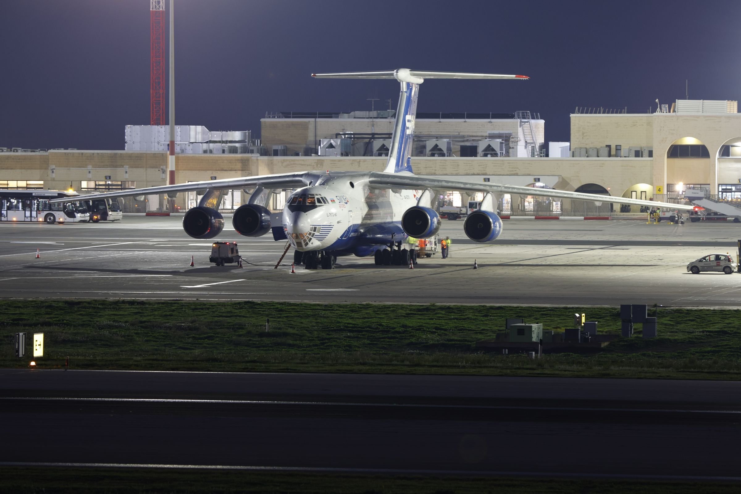 A cargo aircraft parked on a floodlit airport apron at night