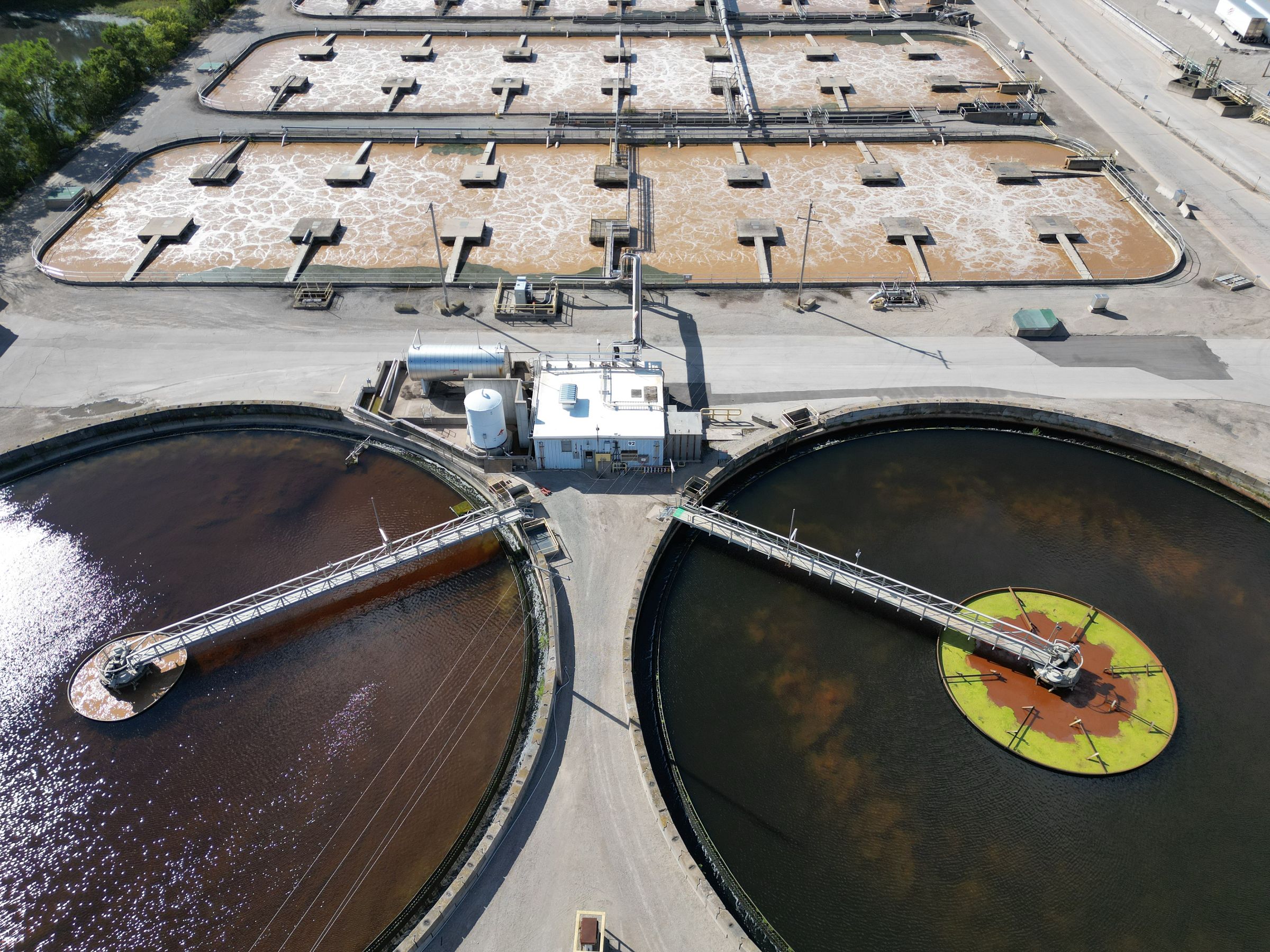 An aerial view of two large circular settling tanks with rotating bridges at a water treatment works.