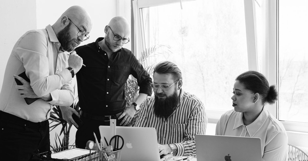 A small team gathered around laptops in a collaborative review session