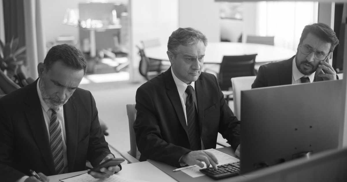 Security leaders in business attire reviewing information at office monitors