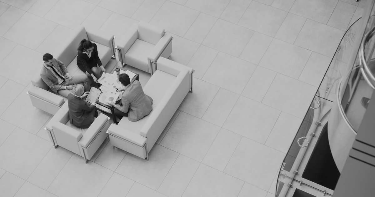 An aerial view of four colleagues reviewing documents around a low table in an office lounge area