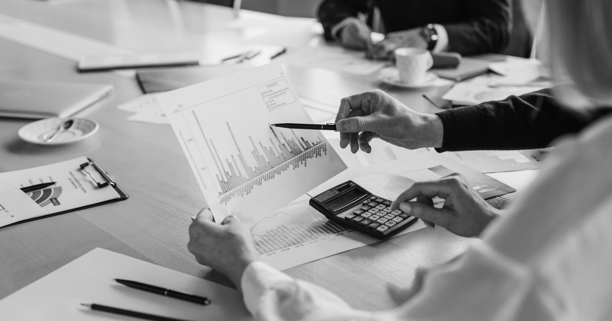 Hands reviewing printed bar charts with a calculator during a budget meeting